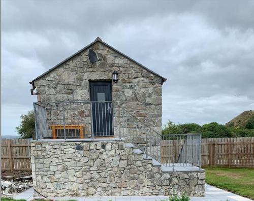 a stone building with a gate and a fence at Cornwall - Unique two storey barn in St Austell