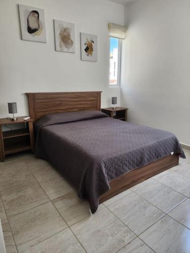 a bedroom with a bed and two tables and a window at Hermoso condominio con alberca en Puerto Morelos in Puerto Morelos