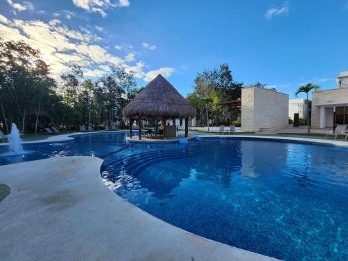 a large swimming pool with a gazebo at Hermoso condominio con alberca en Puerto Morelos in Puerto Morelos