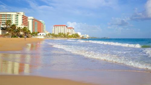 a beach with buildings and the ocean and waves at The Tryst Beachfront Hotel in San Juan