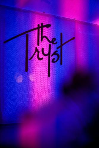 a neon sign with the words it is on a wall at The Tryst Beachfront Hotel in San Juan
