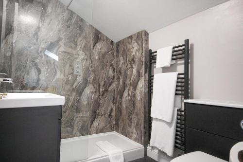 a bathroom with a rock wall with a toilet and sink at The Five Dials Inn in Ilminster