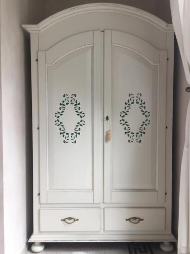 a white cabinet with two wreaths on it at B&B Aquilone in Urbino