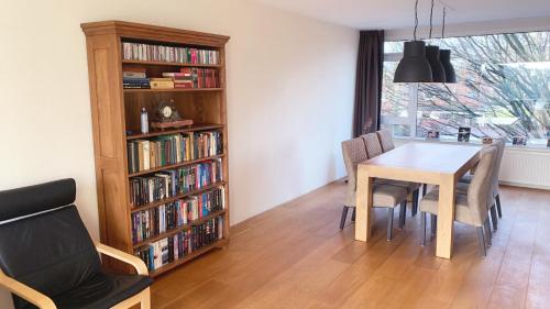 a dining room with a table and chairs and a book shelf at KeyCity Apt Near Amsterdam & The Hague in Leiden