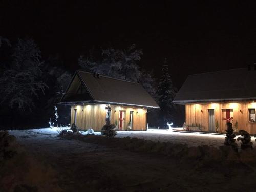 a house with lights in the snow at night at Mała Gorczańska Chatka in Ochotnica Dolna