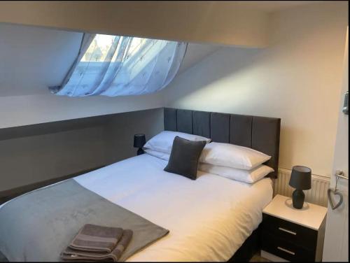 een slaapkamer met een groot wit bed en een raam bij The Willows in Brighouse