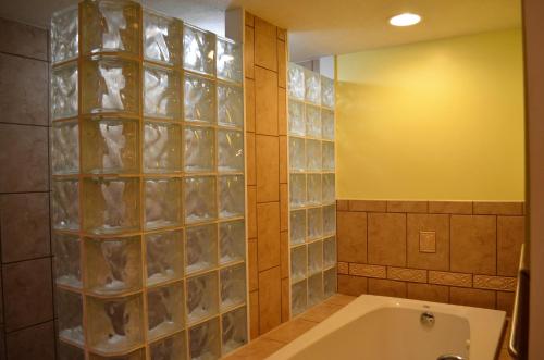 a bathroom with a tub and a glass block wall at Tranquility by the Beach in Key West