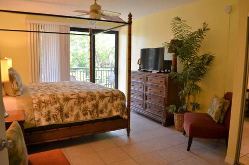 a bedroom with a bed and a dresser with a tv at Tranquility by the Beach in Key West