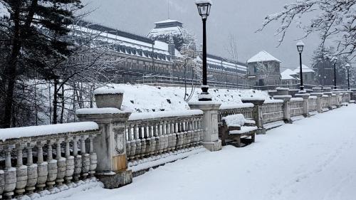 a fence covered in snow with a building in the background at Apartamento Pinsapo Canfranc-Estación in Canfranc-Estación