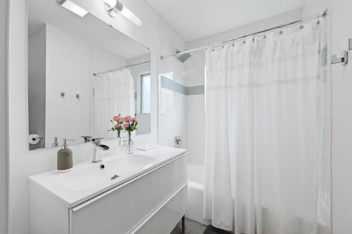 La salle de bains blanche est pourvue d'un lavabo et d'un miroir. dans l'établissement Walk to SoCo Stylish Mid Century Gem by Lodgewell, à Austin