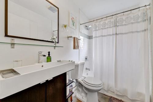 Baño blanco con lavabo y aseo en Sunny Mid Century Modern with Parking Patio and Fenced Yard by Lodgewell, en Austin
