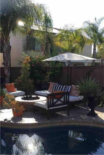 a patio with a bench and an umbrella next to a pool at Vino Villa Large home Sleeps 10! Large Salt water pool/spa in Murrieta