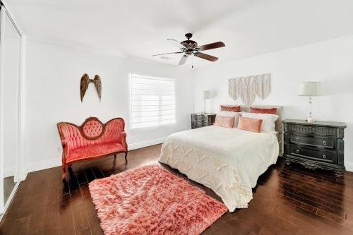 a white bedroom with a bed and a red chair at Vino Villa Large home Sleeps 10! Large Salt water pool/spa in Murrieta