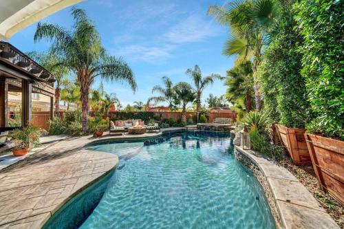 a swimming pool in a backyard with palm trees at Vino Villa Large home Sleeps 10! Large Salt water pool/spa in Murrieta