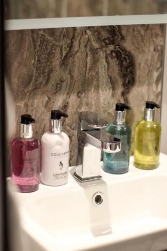 a group of four bottles of soap on a sink at The Five Dials Inn in Ilminster
