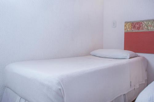 a bedroom with two beds with white sheets at Hotel Praia do Portinho in Ilhabela