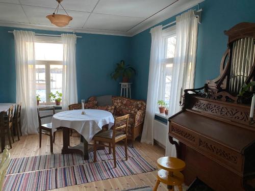 a living room with a table and a piano at Strandgården Hoverberg. in Svenstavik