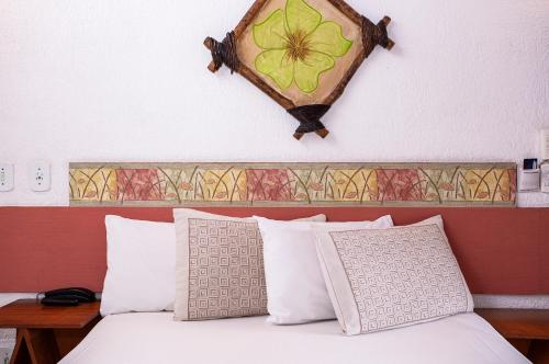 a bedroom with a bed with a flower on the wall at Hotel Praia do Portinho in Ilhabela