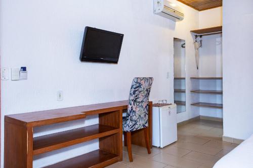 a room with a desk with a tv on the wall at Hotel Praia do Portinho in Ilhabela