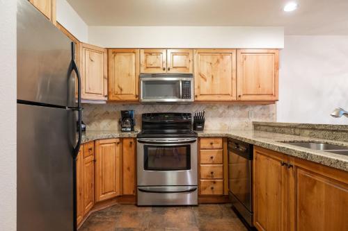 eine Küche mit Holzschränken und Geräten aus Edelstahl in der Unterkunft SNOW FLOWER 149 condo in Park City