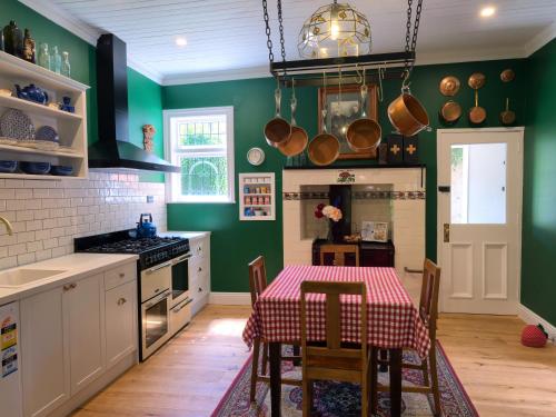 a kitchen with green walls and a table with chairs at The Ferry Bed & Breakfast in Queenstown