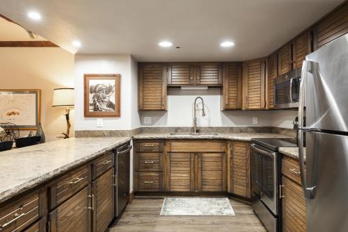 una cucina con mobili in legno e un frigorifero in acciaio inossidabile di PARK STATION 229 condo a Park City