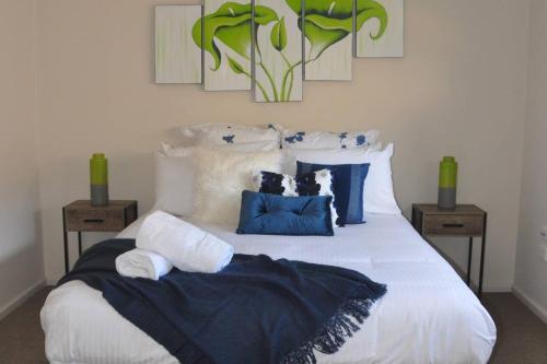um quarto com uma cama branca com almofadas azuis e brancas em Shai Beau em Canadian