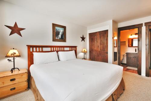 a bedroom with a large white bed and a bathroom at SNOW FLOWER 104 condo in Park City
