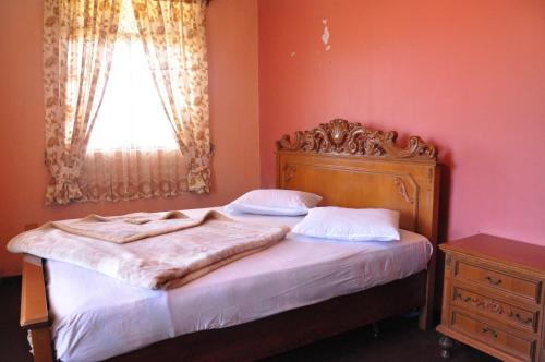 a bedroom with a bed with a wooden headboard and a window at Ragith Villa in Nuwara Eliya