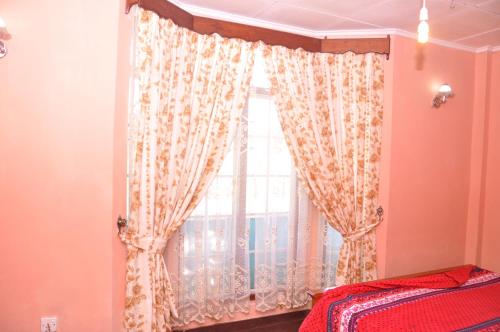 a bedroom with a window with curtains and a bed at Ragith Villa in Nuwara Eliya