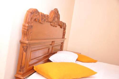 a bed with a wooden head board and two pillows at Ragith Villa in Nuwara Eliya