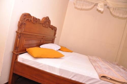 a bed with a wooden headboard and two yellow pillows at Ragith Villa in Nuwara Eliya