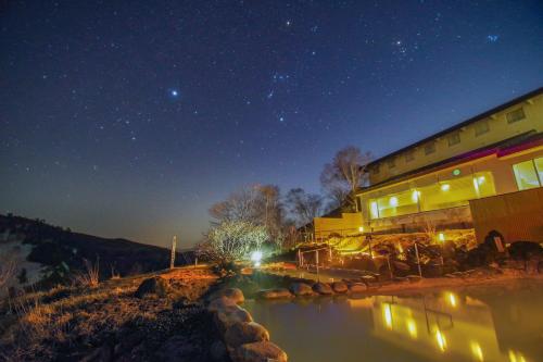 a building with a river in front of it at night at Manza Prince Hotel in Tsumagoi