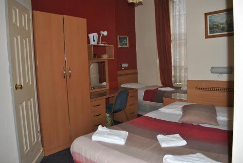 1 dormitorio con 2 camas, escritorio y armario en Guilford House Hotel, en Londres