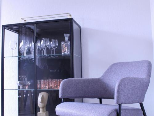a chair next to a glass cabinet with glasses at Retreat near Maasmechelen in Lanaken