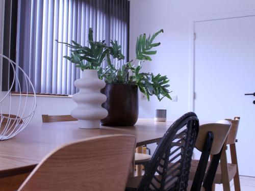 a wooden table with a vase with a plant on it at Retreat near Maasmechelen in Lanaken