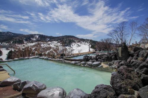 a hot spring in the mountains with snow at Manza Prince Hotel in Tsumagoi