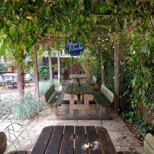 a group of benches sitting under a pergola at The Five Dials Inn in Ilminster