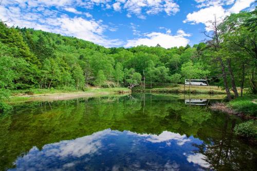 a river with a reflection of the sky in the water at Manza Prince Hotel in Tsumagoi
