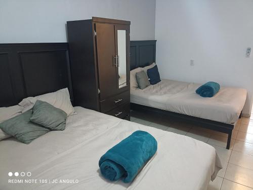 a bedroom with two beds with blue pillows on them at Depa sencillo, 10 min malecon in Mazatlán