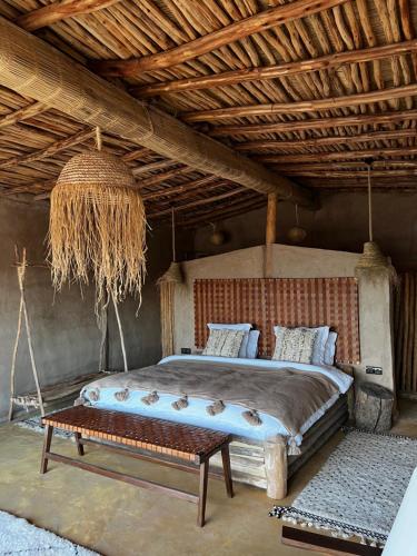 a bedroom with a bed with a bench in it at Alkamar Camp Agafay in El Karia