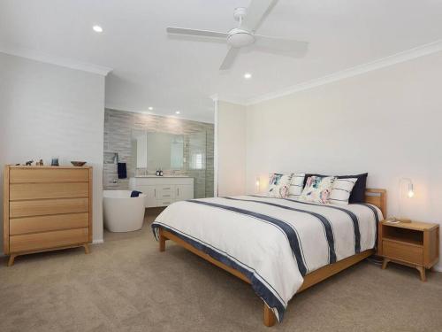 a bedroom with a large bed and a bathroom at The White House Yamba in Yamba
