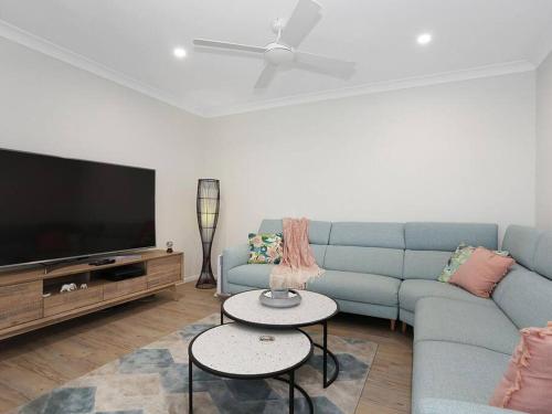 a living room with a blue couch and a flat screen tv at The White House Yamba in Yamba
