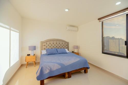 1 dormitorio con 1 cama con manta azul y ventana en Casa Amor en Puerto Vallarta