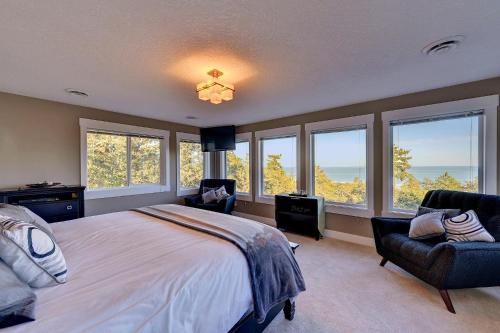 a bedroom with a bed and chairs and windows at Arbutus Hill in Victoria