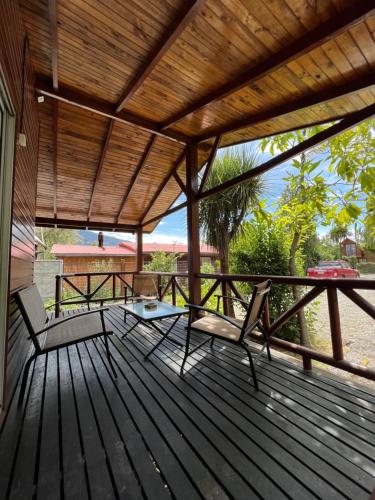 a wooden deck with two chairs and a table at Cabaña Las Patagüas - Coñaripe in Coñaripe