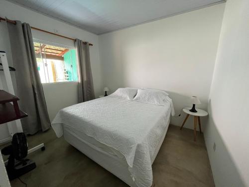 a white bedroom with a bed and a window at Casa Esmeralda in Alto Paraíso de Goiás