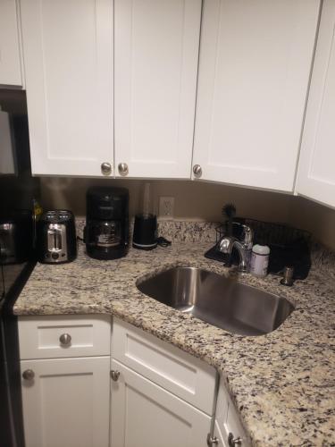 a kitchen counter with a sink and white cabinets at The Airport Lodge in Collingdale
