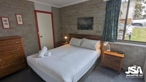 a bedroom with a white bed and a window at Tanderra 4 in Jindabyne