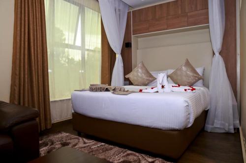 a bedroom with a large white bed with a window at Hylise Hotel in Naivasha